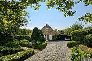 A house with a paved driveway leading to a garage, surrounded by well-maintained hedges and a variety of shrubs. - Holiday home in Aagtekerke with Wi-Fi (Aagtekerke)