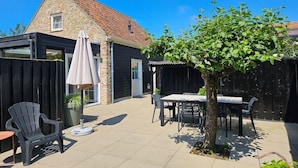 Un espace patio avec une table et des chaises, une plante en pot et un arbre.