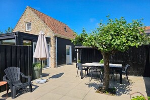 A patio area with a table and chairs, a potted plant, and a tree. - Holiday home in Aagtekerke with Wi-Fi (Aagtekerke)