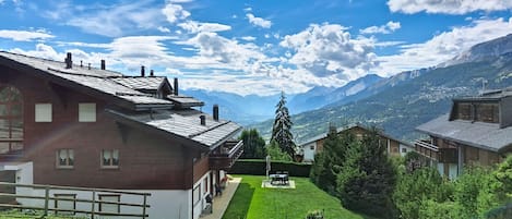A residential area with houses, a well-maintained lawn, and a mountain view.