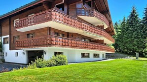 A multi-story wooden chalet with balconies, a garage, and a well-maintained lawn. - Résidence Mila n°2 by Interhome (Crans-Montana)