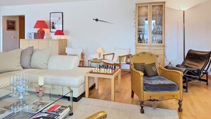A living room with a sofa, armchairs, a coffee table, a chessboard, a cabinet with glass doors, and a lamp. - Résidence Mila n°2 by Interhome (Crans-Montana)