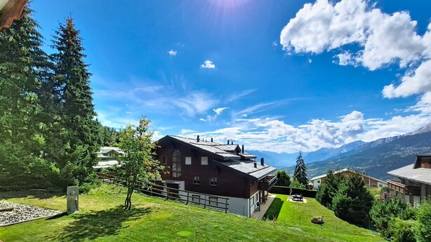 A house with a sloped roof, a well-maintained lawn, and a mountain view. - Résidence Mila n°2 by Interhome (Crans-Montana)