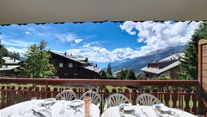 A terrace with tables set for dining, overlooking a mountainous landscape. - Résidence Mila n°2 by Interhome (Crans-Montana)