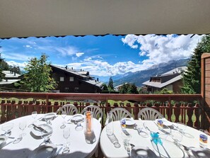 Een terras met gedekte tafels, met uitzicht op een bergachtig landschap.