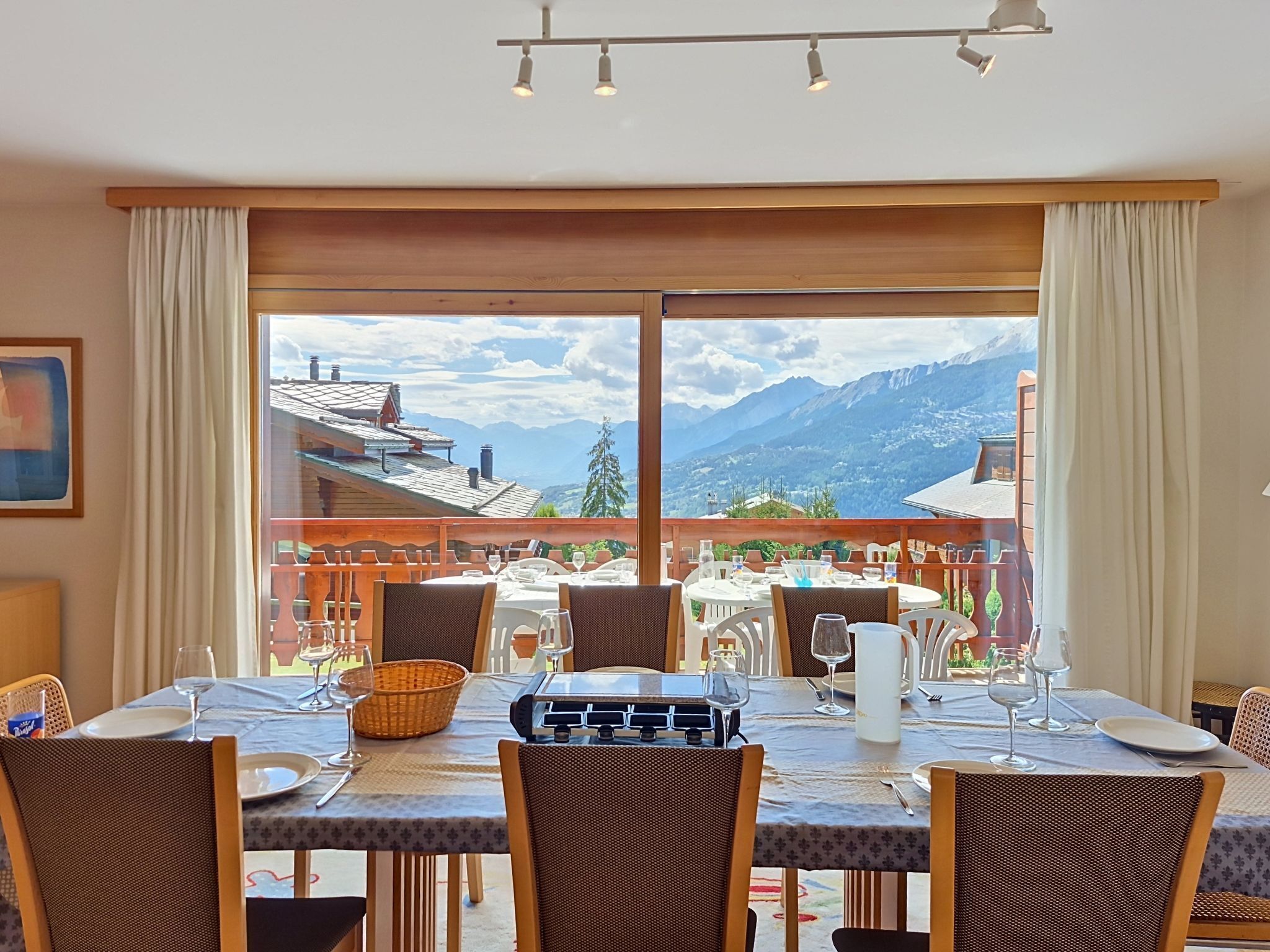 A dining area with a table set for four, overlooking a mountainous landscape.