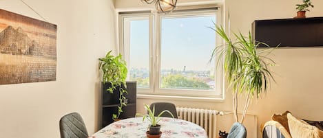 Ruokailutila, jossa on pöytä, tuoleja, patteri ja ikkuna, josta avautuu näkymä kaupunkiin.