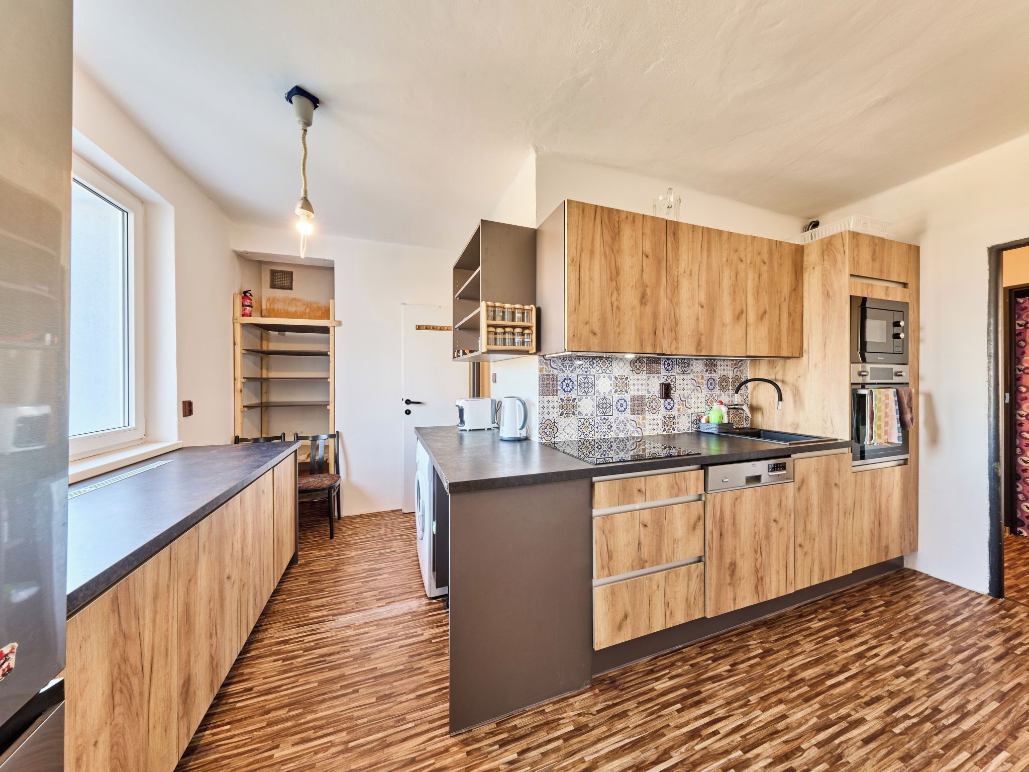 A modern kitchen with wooden cabinets, a built-in oven, and a tiled backsplash.