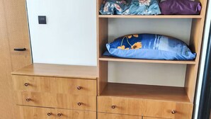 Un mueble de madera con cajones y estantes, una puerta con picaporte, y suelo de madera.