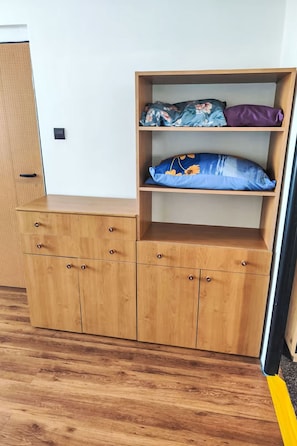 A wooden cabinet with drawers and shelves, a door with a handle, and a wooden floor.