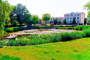 Ein angelegter Garten mit Teich, gepflegten Rasenflächen und einem großen Gebäude im Hintergrund.