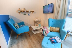 Ein modernes Wohnzimmer mit einem blauen Sofa, einem Couchtisch und einem flachbildfernseher an der Wand.