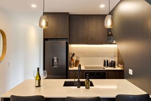 A modern kitchen with a central island, dark cabinetry, and pendant lighting. - Prime Location with mountain views (Queenstown)