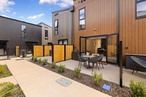 A modern building with a patio area featuring a table and chairs. - Prime Location with mountain views (Queenstown)