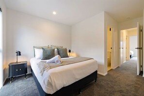 A hotel room with a large bed, a bedside table with a lamp, and a carpeted floor. - Prime Location with mountain views (Queenstown)