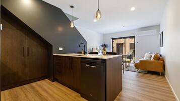 A modern kitchen with dark cabinetry, a dishwasher, and pendant lighting.
