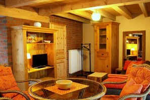 A cozy room with a television, wooden cabinets, and wicker furniture. - "PROVENCE" in the half-timbered house in Waren (Waren)