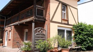 Een klassiek pand met een houten balkon, een bakstenen gevel en bloempotten.