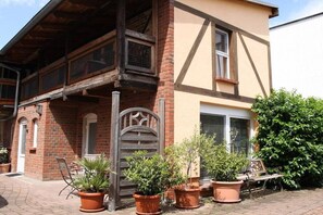 A traditional building with a wooden balcony, a brick facade, and potted plants. - "PROVENCE" in the half-timbered house in Waren (Waren)