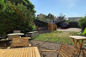 An outdoor seating area with wooden furniture, a small wooden structure, and a car parked in the background. - "PROVENCE" in the half-timbered house in Waren (Waren)