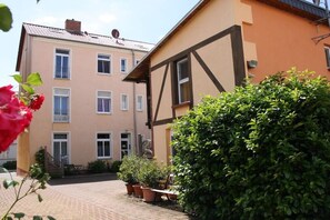 A two-story building with a balcony, potted plants, and a brick pathway. - "PROVENCE" in the half-timbered house in Waren (Waren)