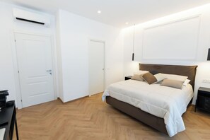Un dormitorio con cama, mesitas de noche, un escritorio y un equipo de aire acondicionado.