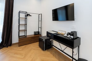 A modern room with a desk, a flat-screen TV, a ladder, a safe, and a coffee machine. - Sweet Home 36-Vatican (Rome)