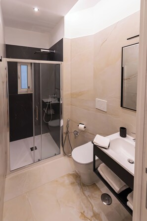 Un baño moderno con ducha de vidrio, inodoro y lavamanos con espejo.
