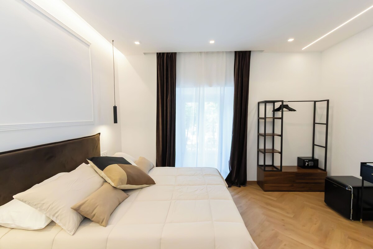 Habitación de hotel con una cama grande, un armario, un escritorio y una ventana con cortinas.