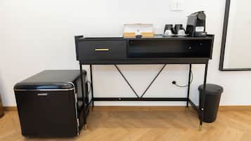 A black desk with a laptop, a coffee maker, and a trash bin.