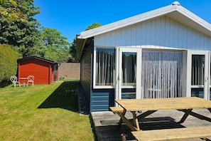 A small, single-story building with a sloped roof, a front door, and a large window. - OK11 Bungalow Oostkapelle (Oostkapelle)