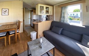 Een knus woongedeelte met een kitchenette, een eethoek en een bank.