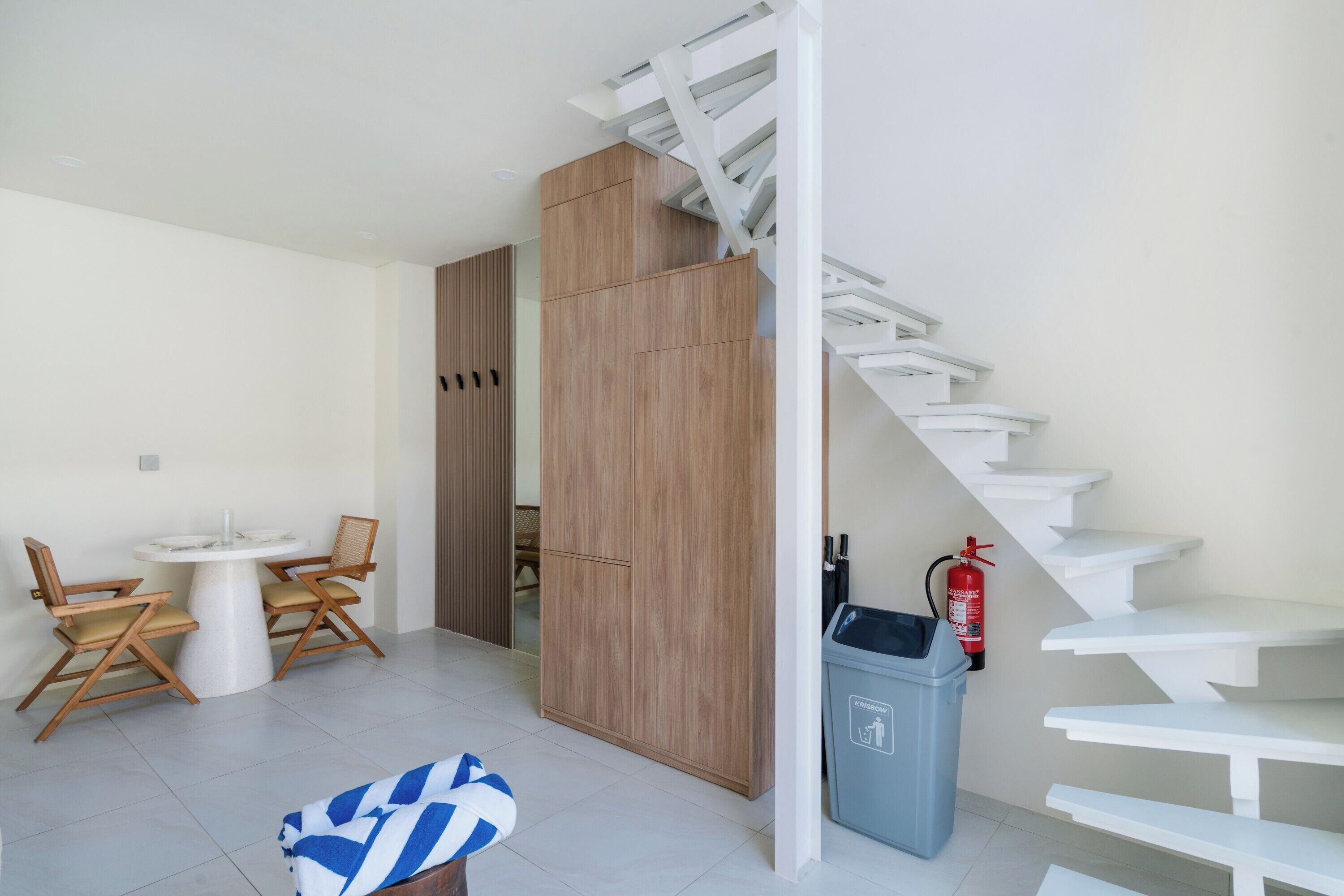 Interior moderno com escada, área de jantar e lixeira.