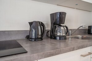 Eine Küche mit Kaffeemaschine, Wasserkocher und Spüle.