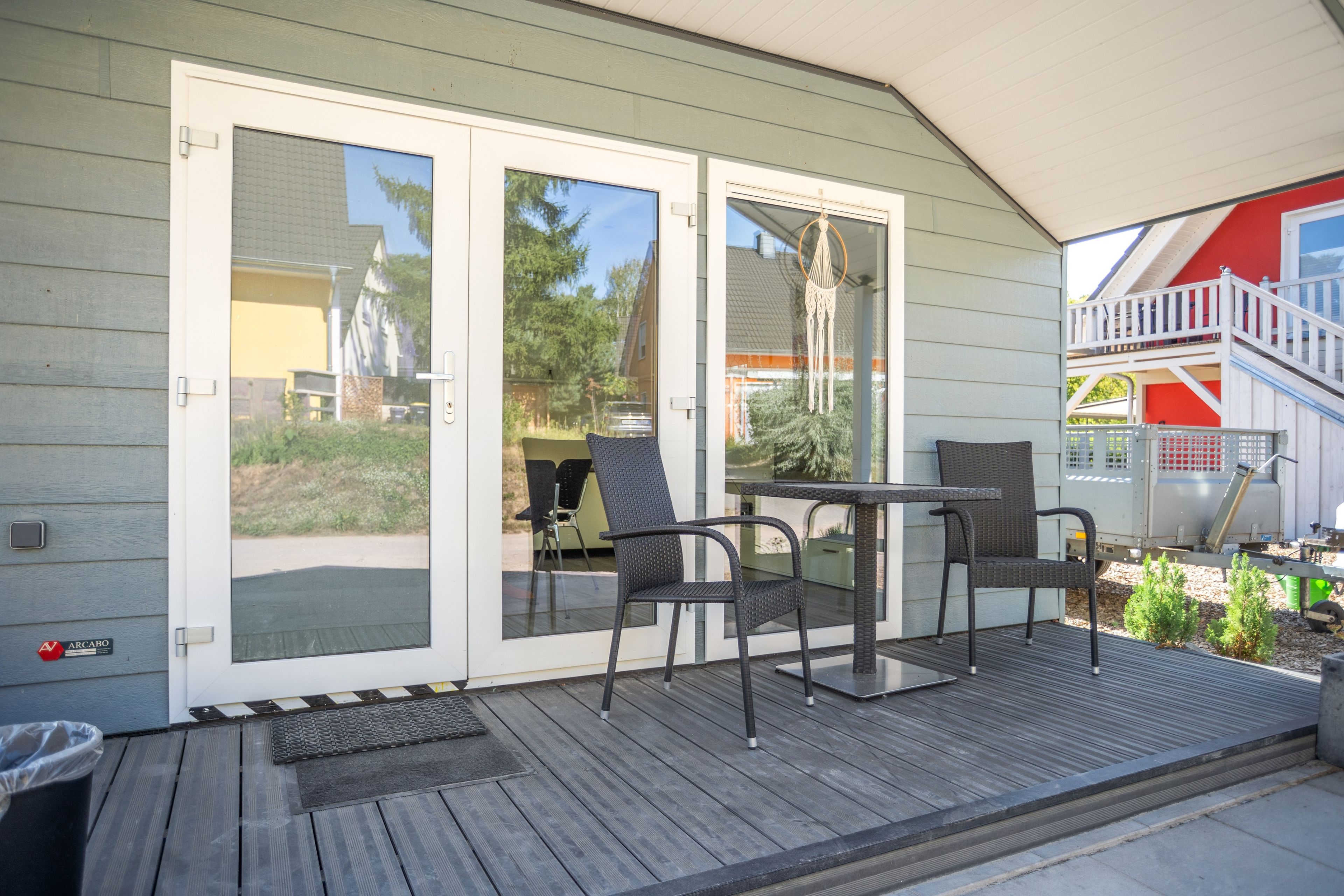 Une terrasse couverte avec une table et des chaises, une porte-fenêtre coulissante et un petit espace extérieur agrémenté de plantes.