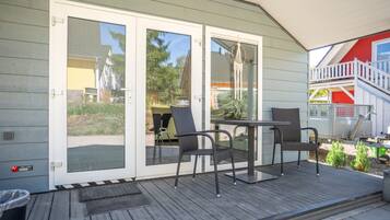 Une terrasse couverte avec une table et des chaises, une porte-fenêtre coulissante et un petit espace extérieur agrémenté de plantes.