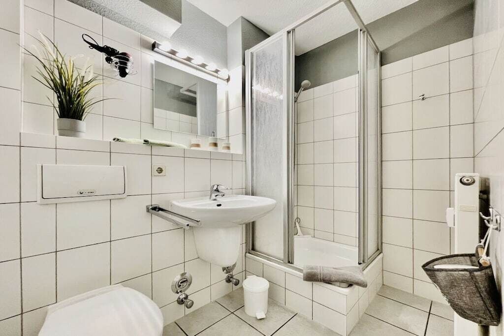 Een moderne badkamer met een wastafel, spiegel en douche.