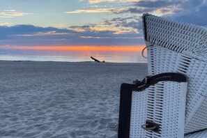 A beach scene with a wicker chair and a surfboard. - Holiday apartment with 1 bedroom (Dierhagen)