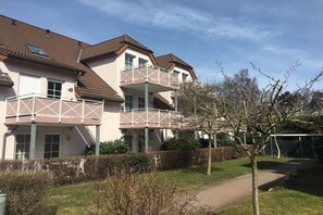 Een woongebouw met meerdere balkons, een verhard pad en een verzorgde tuin.