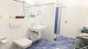 Un baño con un lavamanos blanco, un inodoro, una ducha con cortina azul y una bañera blanca.