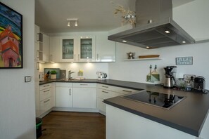 A modern kitchen with white cabinetry, a black countertop, and a stainless steel range hood. - Exclusive tower apartment (Burgtiefe)