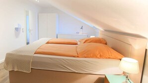 Un dormitorio con cama, mesita de noche, lámpara y armario.