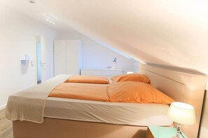 A bedroom with a bed, a nightstand, a lamp, and a wardrobe. - Exclusive tower apartment (Burgtiefe)