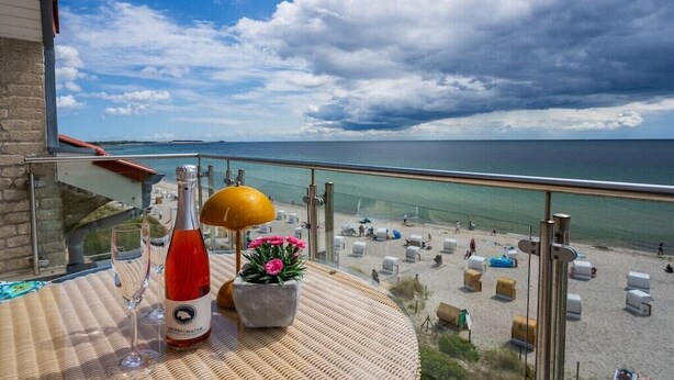 Un balcón con una botella de vino tinto, una copa y una maceta.