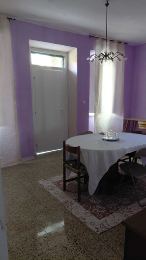 A dining area with a round table, chairs, a chandelier, and a patterned rug.