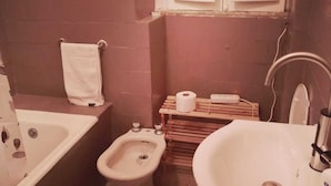Een compacte badkamer met een bad, toilet, wastafel en bidet.