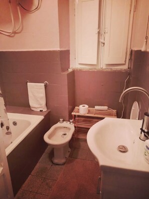 Een compacte badkamer met een bad, toilet, wastafel en bidet.