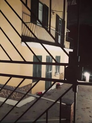 A building with a balcony, a staircase, and a window with shutters.