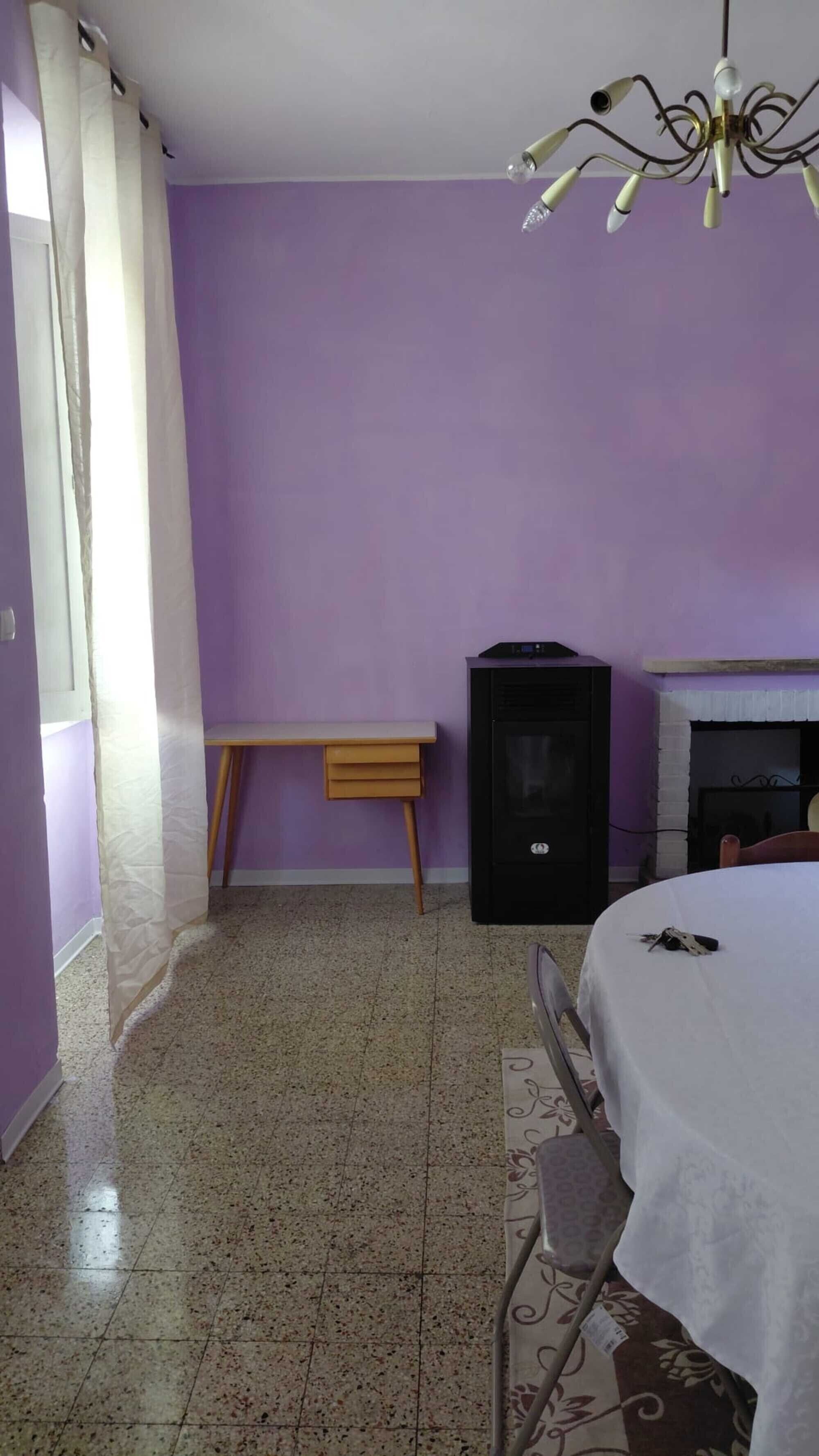 Ein Zimmer mit einem Bett, einer kleinen Holzbank, einem schwarzen Lautsprecher und einem Kamin.