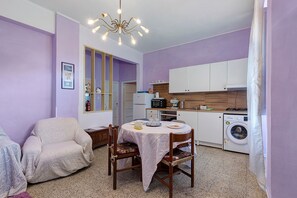 Espai habitable compacte amb zona de menjador, petita cuina i rentadora.